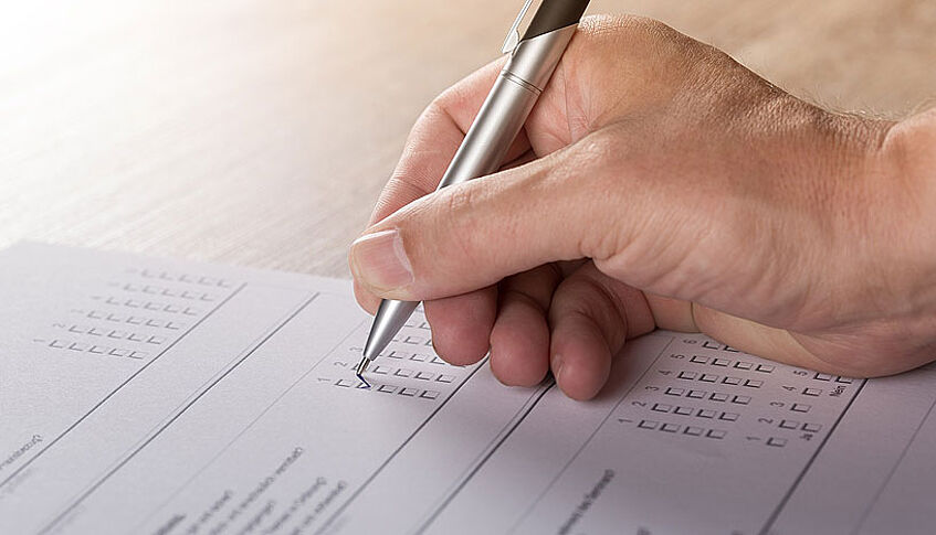 Hand und Kugelschreiber beim Ausfüllen eines Fragebogens