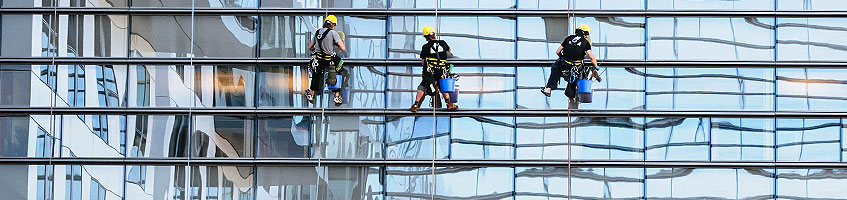 Fensterputzer vor der Glasfront eines Bürogebäudes